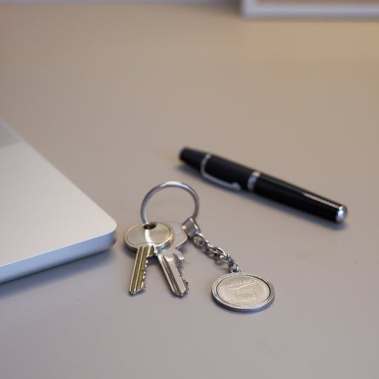 Schlüsselanhänger - Heritage - silberfarben - Freimünze Nr. 3 auf Schreibtisch vor Laptop und Kugelschreiber