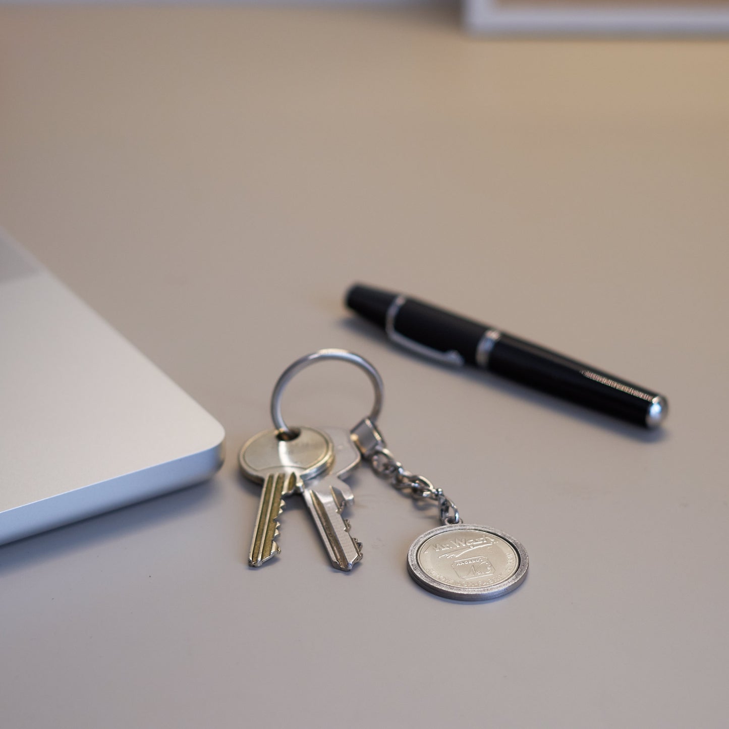 Schlüsselanhänger - Heritage - silberfarben - Freimünze Nr. 3  auf Schreibtisch vor Laptop und Kugelschreiber